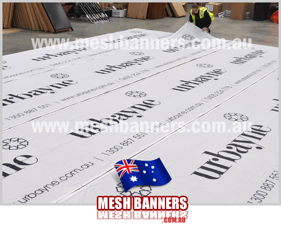 Woman checking the new Urbayne temporary fencing banner signs. Each temporary fence banner sign is used as builders dust and privacy screening during the construction of new homes and renovations around melbourne australia. We supply cheap banner signs melbourne and australia wide including temporary fencing banner signs and mesh banners for building