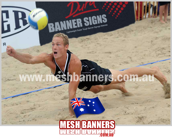 Man diving into the sand whilst attempting to return the beach volley ball The banner sign is in the background on the fence. Event and Sport sponsorship and signage supplies