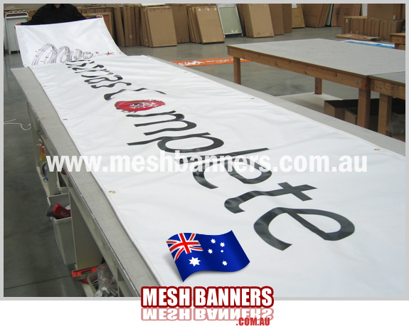 Person rolling out a long banner sign on the workbench