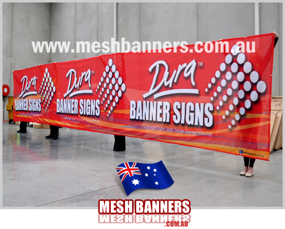People holding up large mesh banner sign
